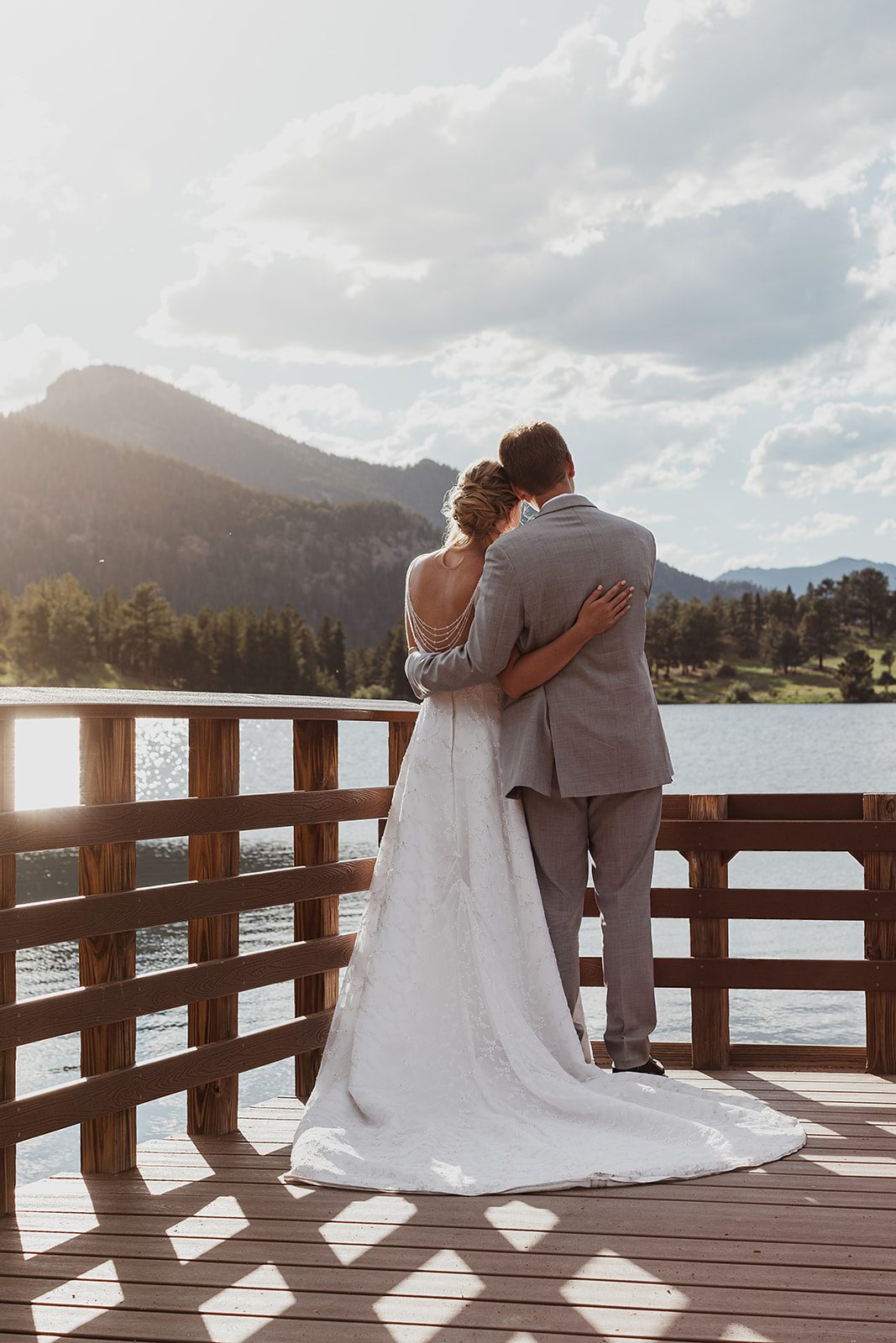 Bride and groom wedding portrait hugging on the bridge, overlooking a lake and mountains