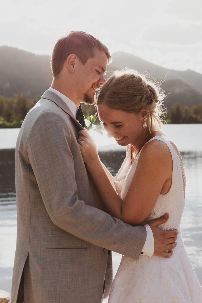 Bride and groom smiling at each other with a beautiful lake and mountains in the backdrop