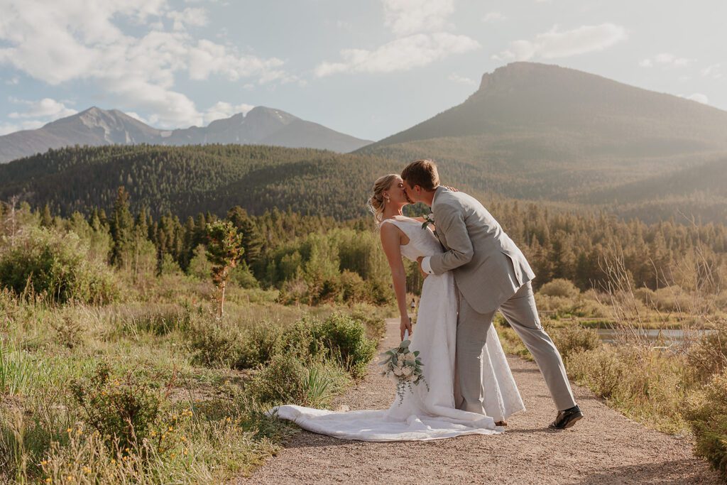Bride and groom kissing photo at a beautiful landscape with loads of greenery and mountains