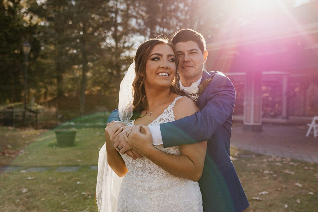 Groom hugging bride from behind during their wedding portrait photosession