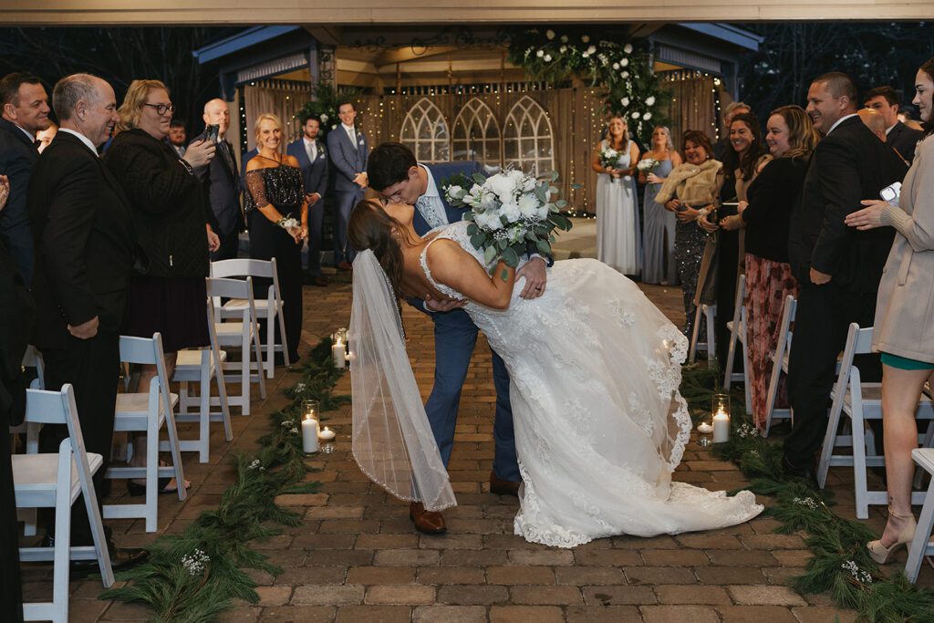 Groom dipping and kissing his bride at the end of the aisle post ceremony