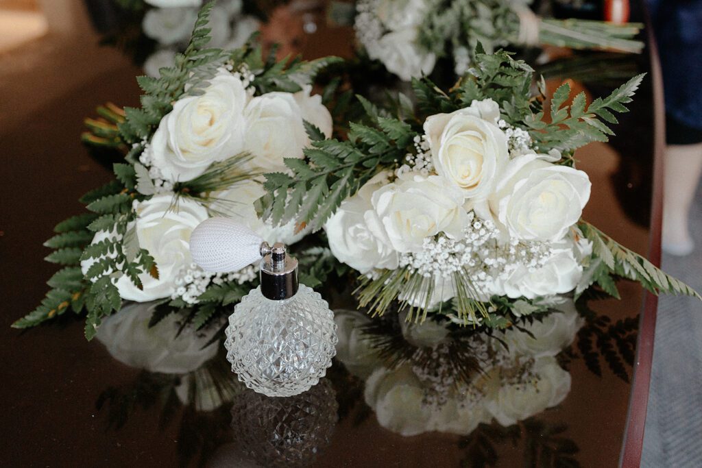 Detail shot of perfume and wedding bouquets made of white roses