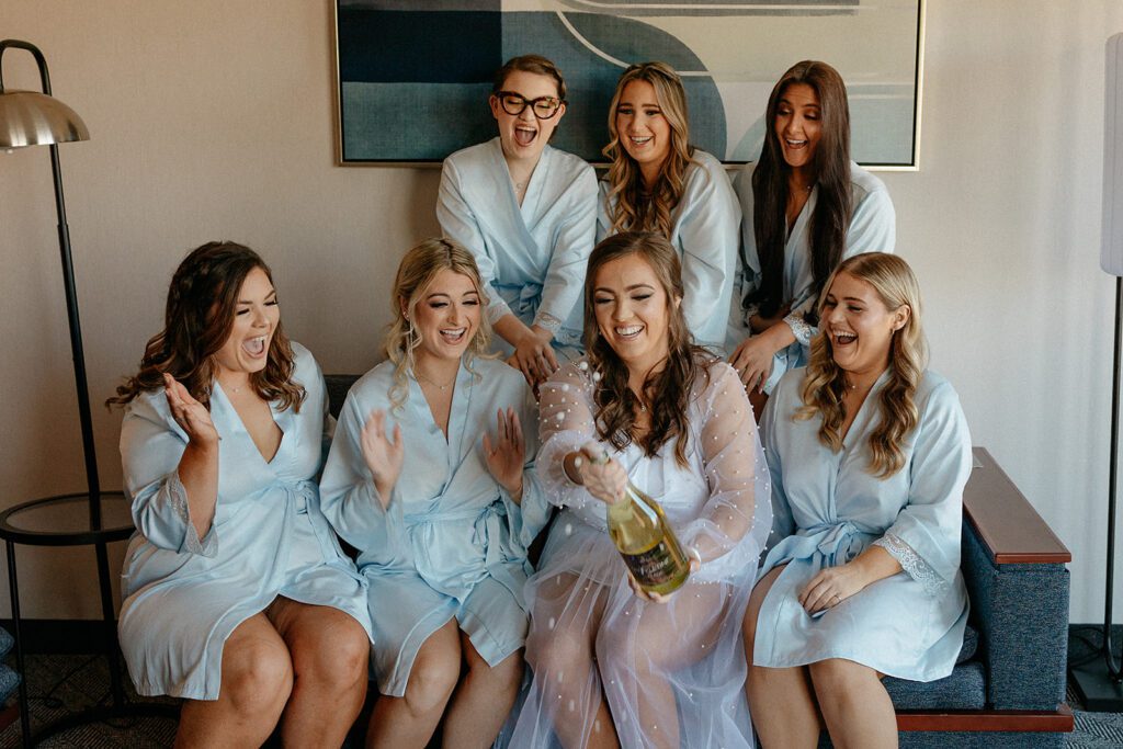 Bride popping champagne with her bridesmaids