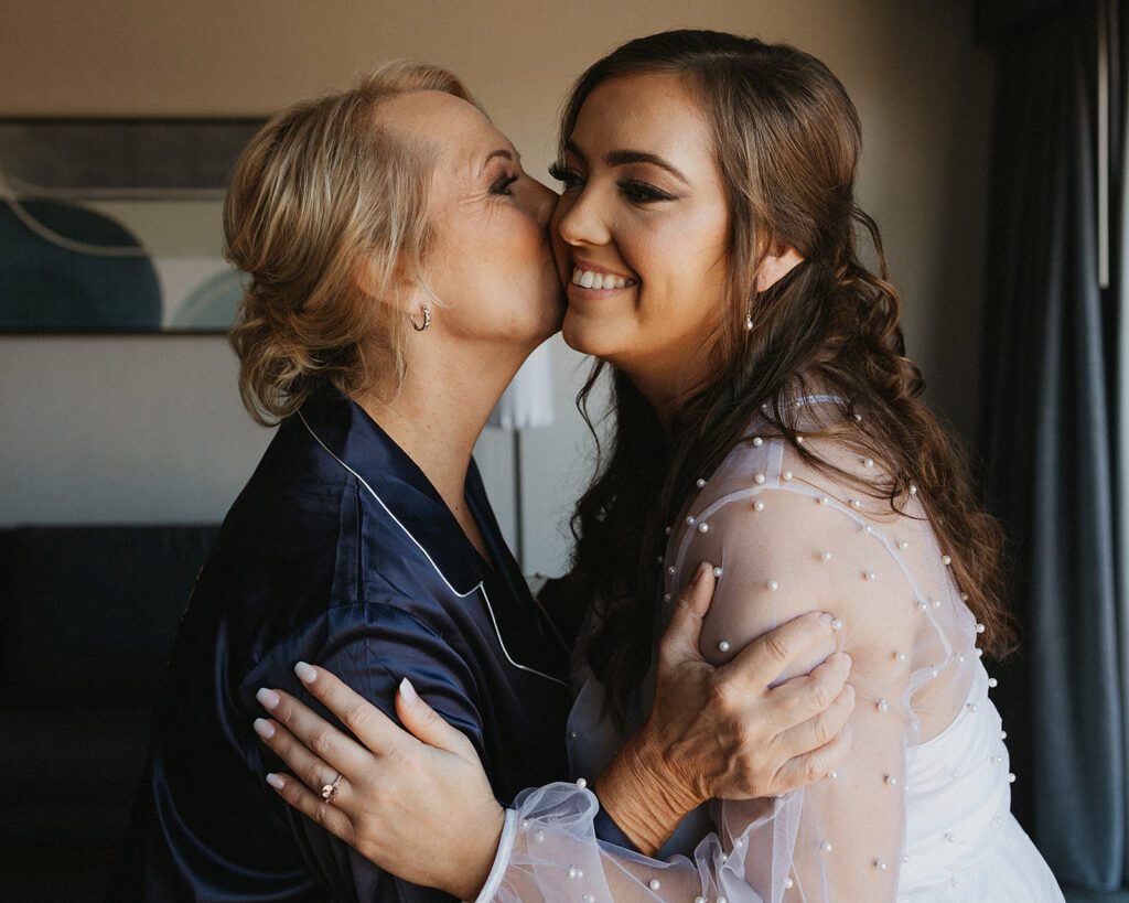 Mom of the bride kissing bride on the cheek