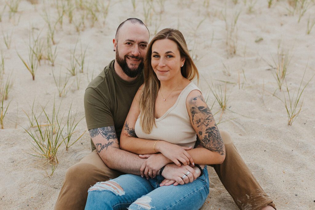 Couple sitting in the sand together during their Sandy Hook beach engagement shoot