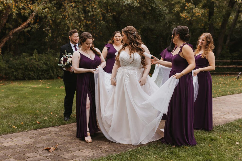Lively group photo of bridesmaids in elegant purple dresses and groomsmen in purple ties, celebrating a Jewish wedding at a country club
