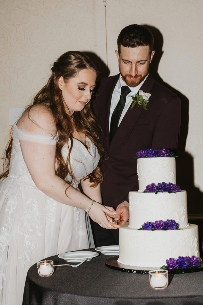 Bride and groom joyously cutting their wedding cake, a sweet moment at their Jewish country club wedding