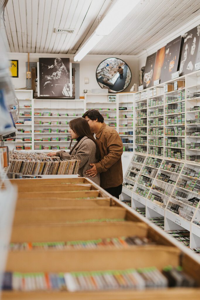 Alexa and Joe sharing a romantic moment while shuffling through vintage records in a record store on a date night in Palmer Square