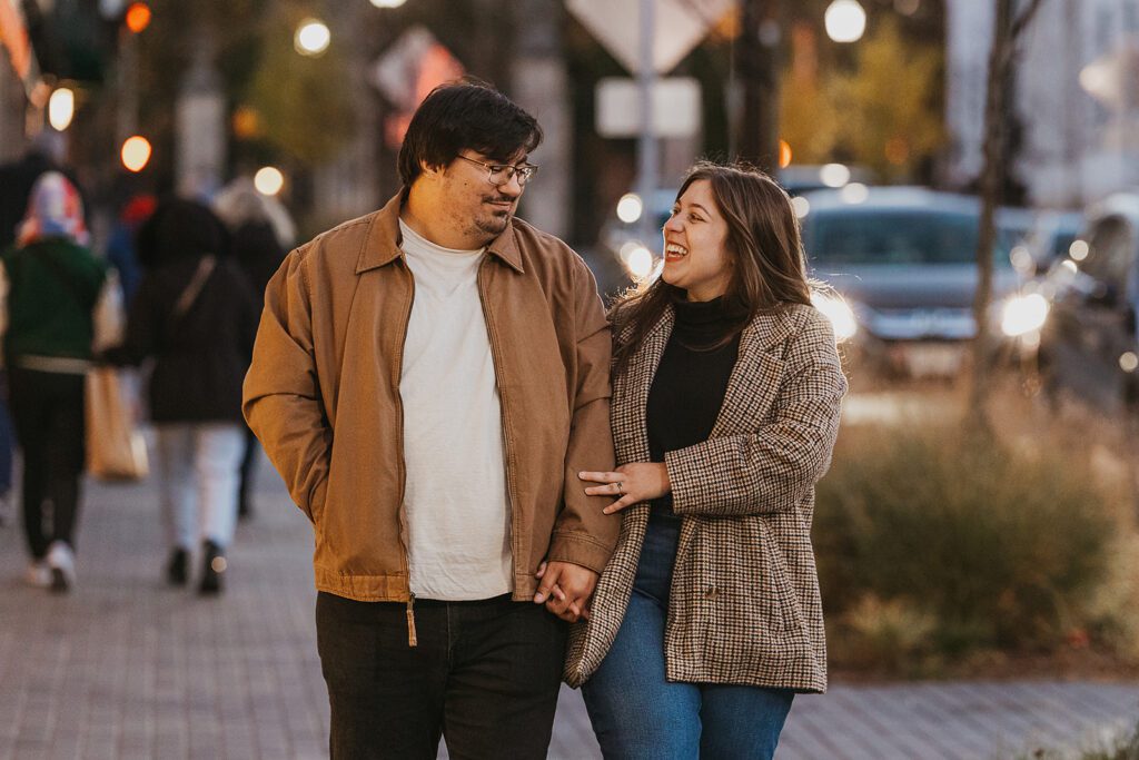 A heartwarming scene of Alexa and Joe holding hands, exploring the quaint shops of Palmer Square, with fall's golden light casting a magical glow