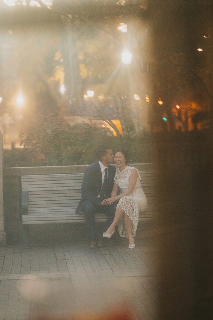The future bride and groom sharing a cuddle on a park bench 