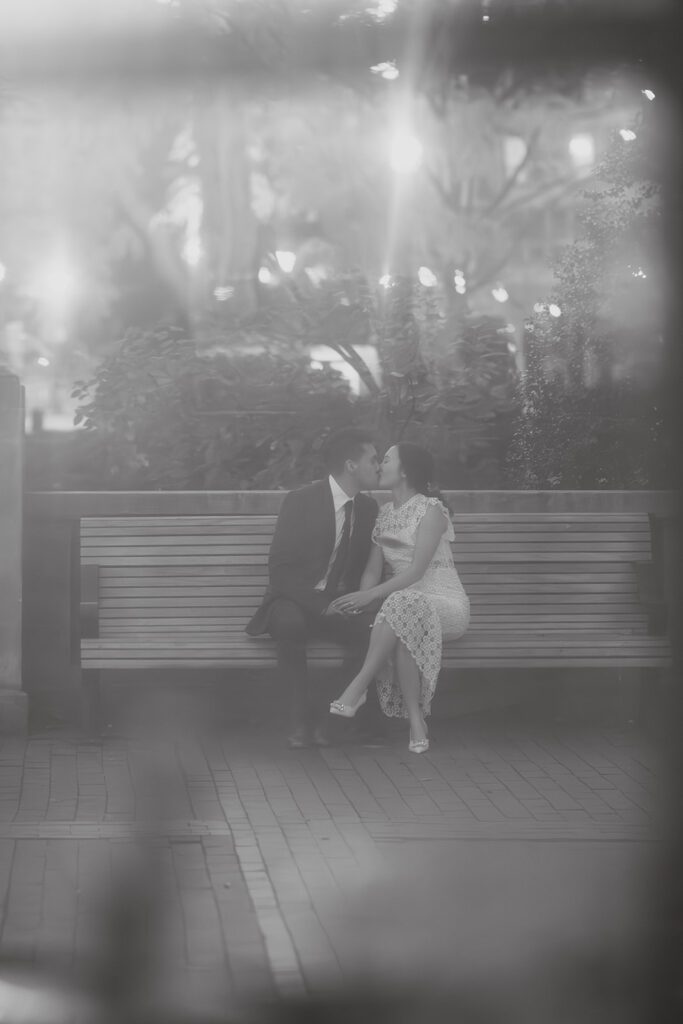 The future bride and groom sharing a cuddle on a park bench 