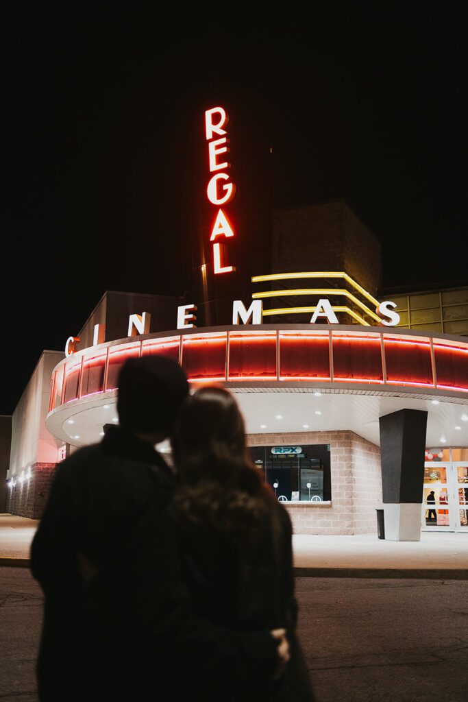 Engaged couple, Christine and Joe, sharing a casual and fun moment in a vintage movie theater, highlighting the unique theme of their movie theater engagement photos