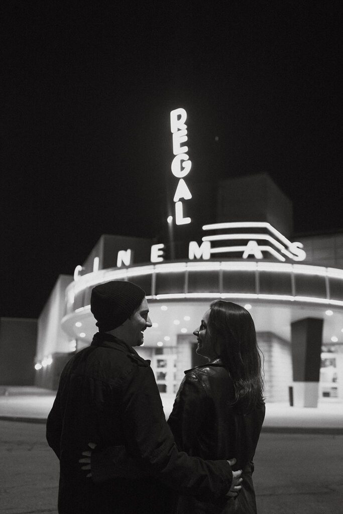A playful embrace captured outside an iconic movie theater, with Christine and Joe's laughter echoing the fun and casual theme of their engagement shoot