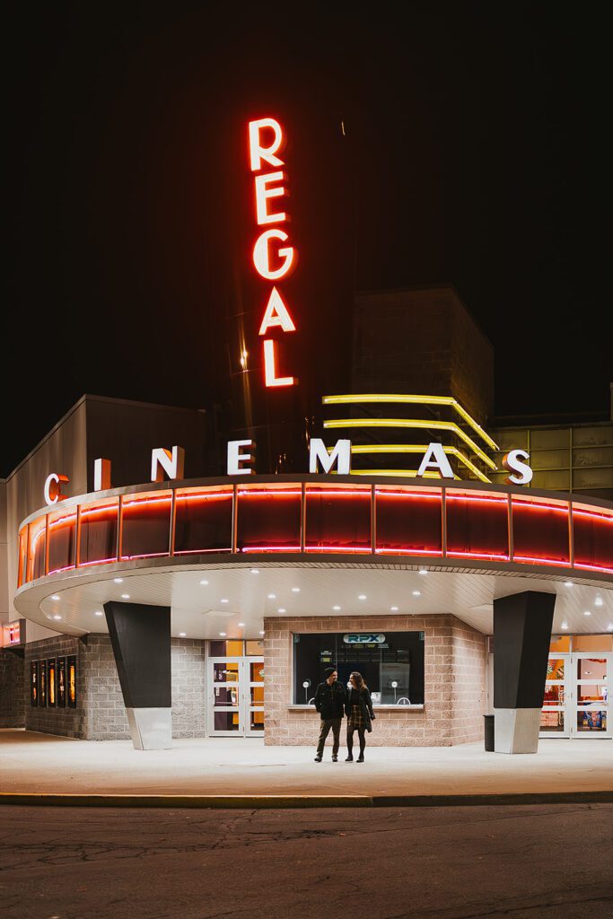 Engaged couple, Christine and Joe, sharing a casual and fun moment in a vintage movie theater, highlighting the unique theme of their movie theater engagement photos
