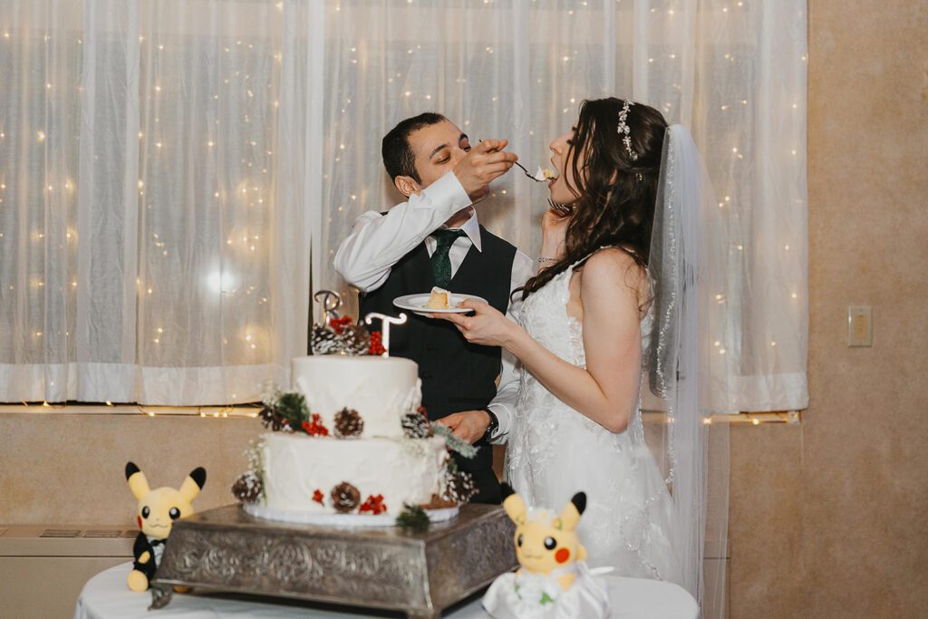 bride and groom cutting their wedding cake decorated with winter wedding details and pokemon