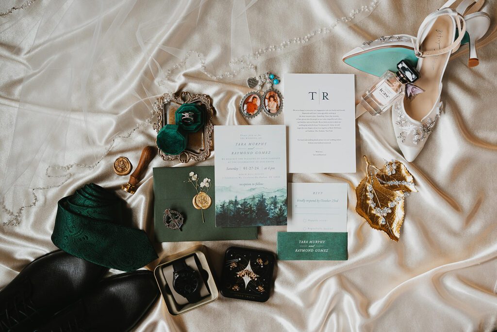 elegant winter wedding detail flatlay featuring dark greens, gold and silver 