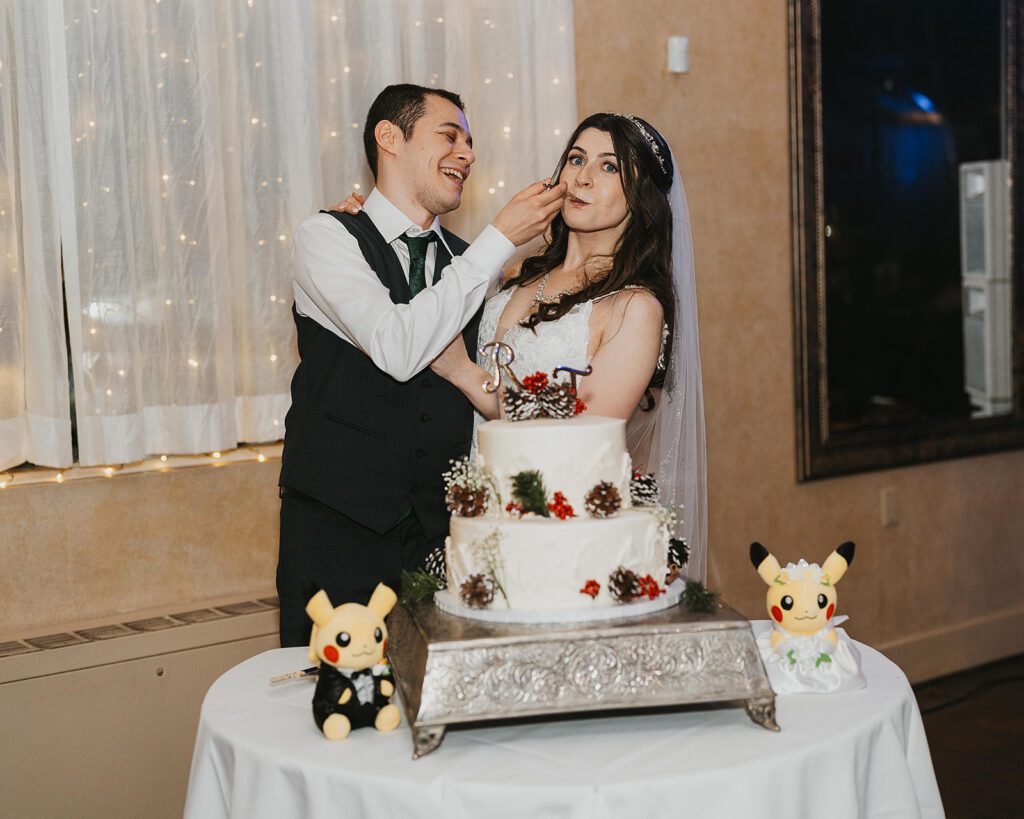 bride and groom cutting their wedding cake decorated with winter wedding details and pokemon