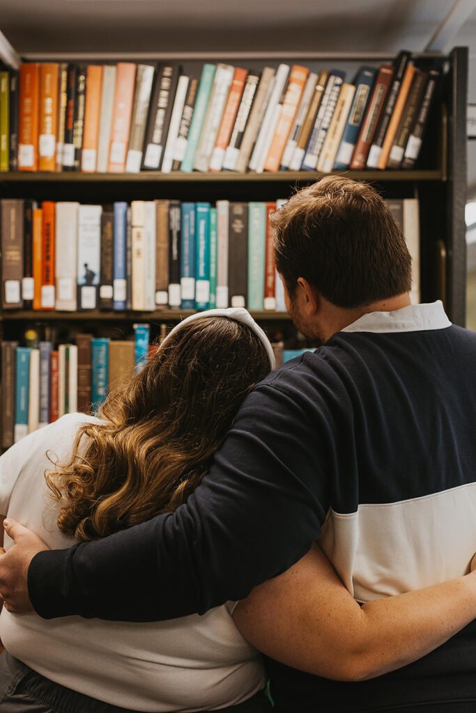 a couple browsing through books together for their library engagement photos