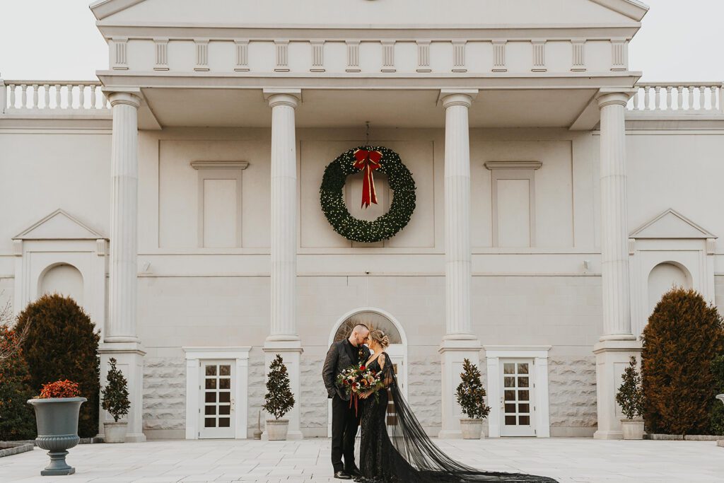  bride and groom in an all black wedding attire posing in front of the elegant Palace at Somerset Park creating a fun contrast between the dark and the light