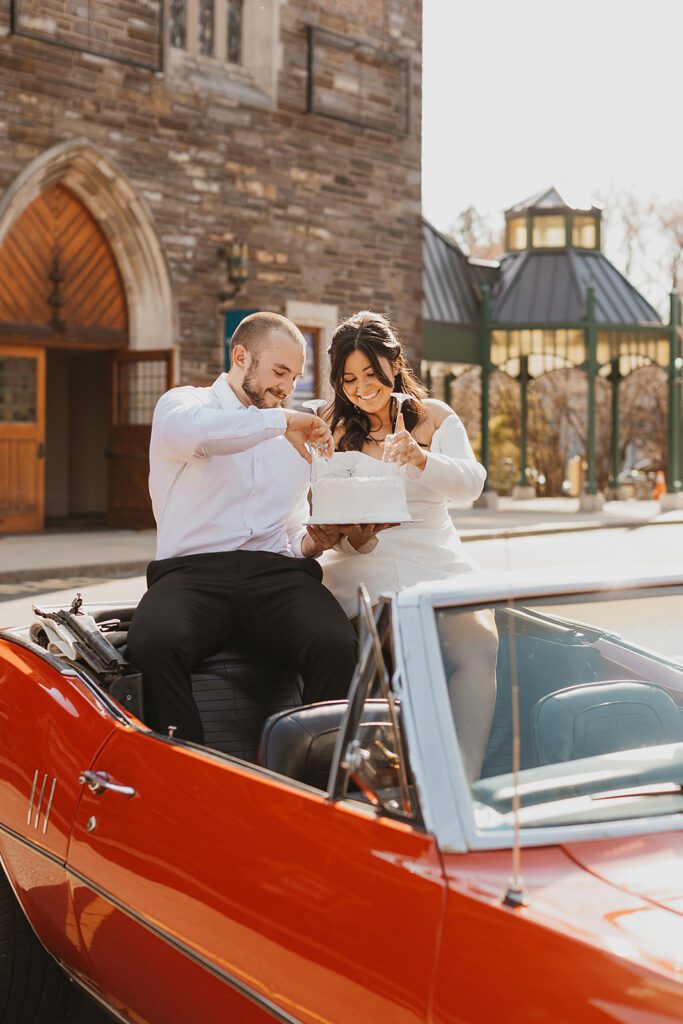 couple eating cake together sitting in a vintage convertible