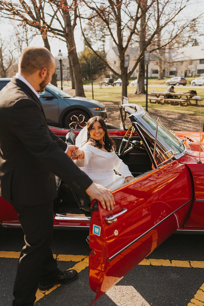 romantic couple celebrating their engagement with a red vintage convertible