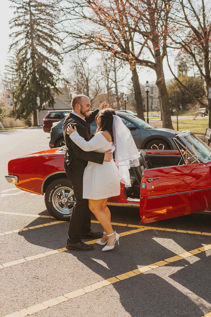 romantic couple celebrating their engagement with a red vintage convertible