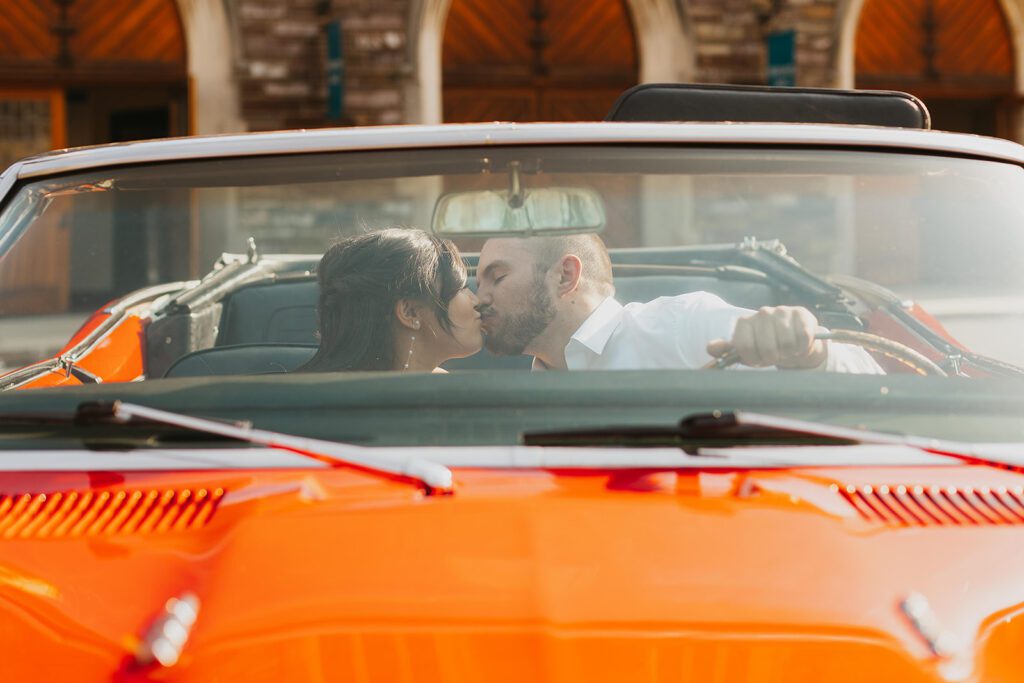 couple kissing in a vintage red convertible car