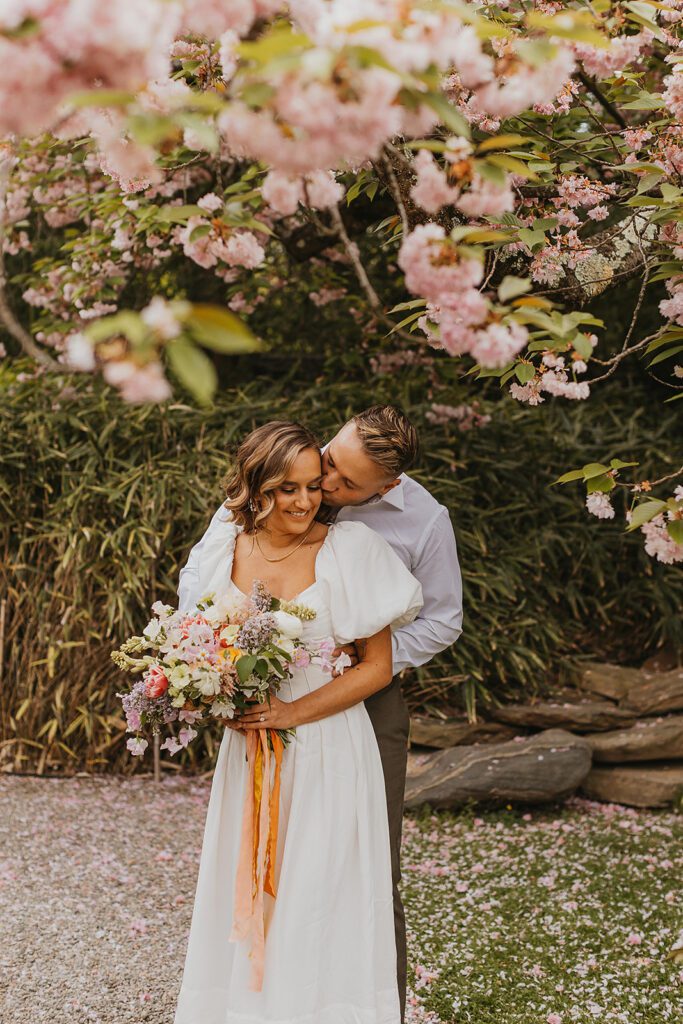 candid engagement photos in cherry blossoms