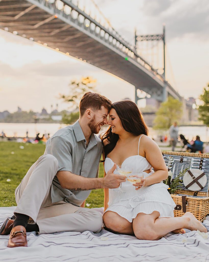 an engaged couple toasting champagne in a park