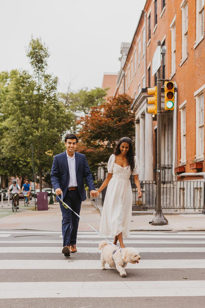 engaged couple walking their dog in downtown philadelphia for their candid engagement photos