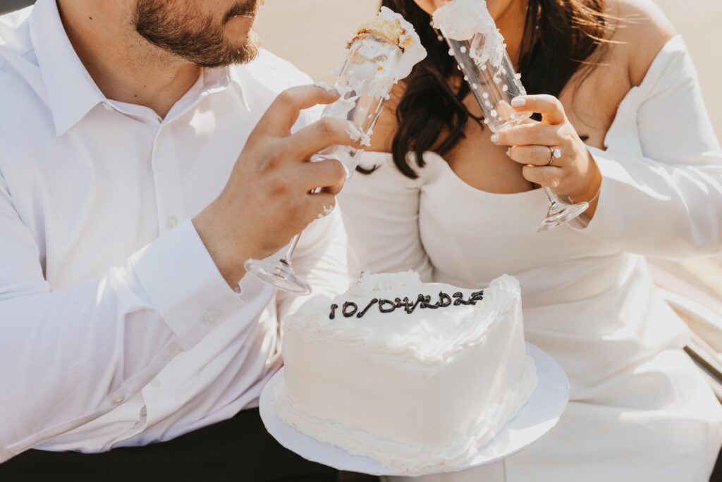 candid photo of couple eating cake with champagne galsses