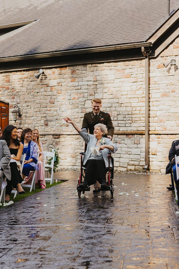 Grandma as a flower girl is going down the aisle in a wheelchair sprinkling petals on the aisle