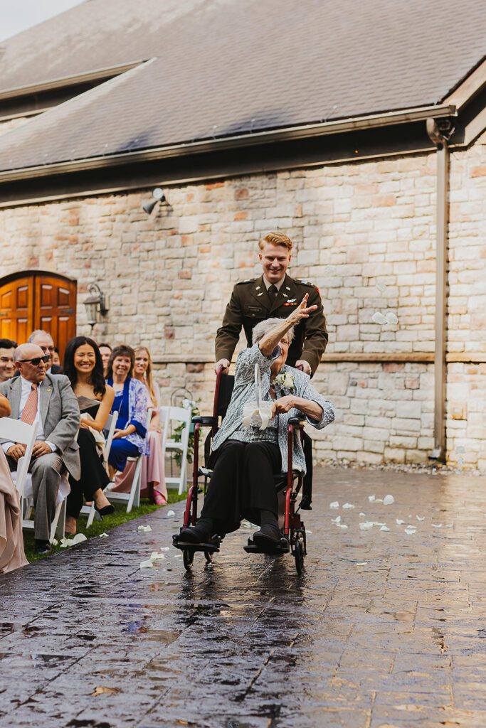 Grandma as a flower girl is going down the aisle in a wheelchair sprinkling petals on the aisle