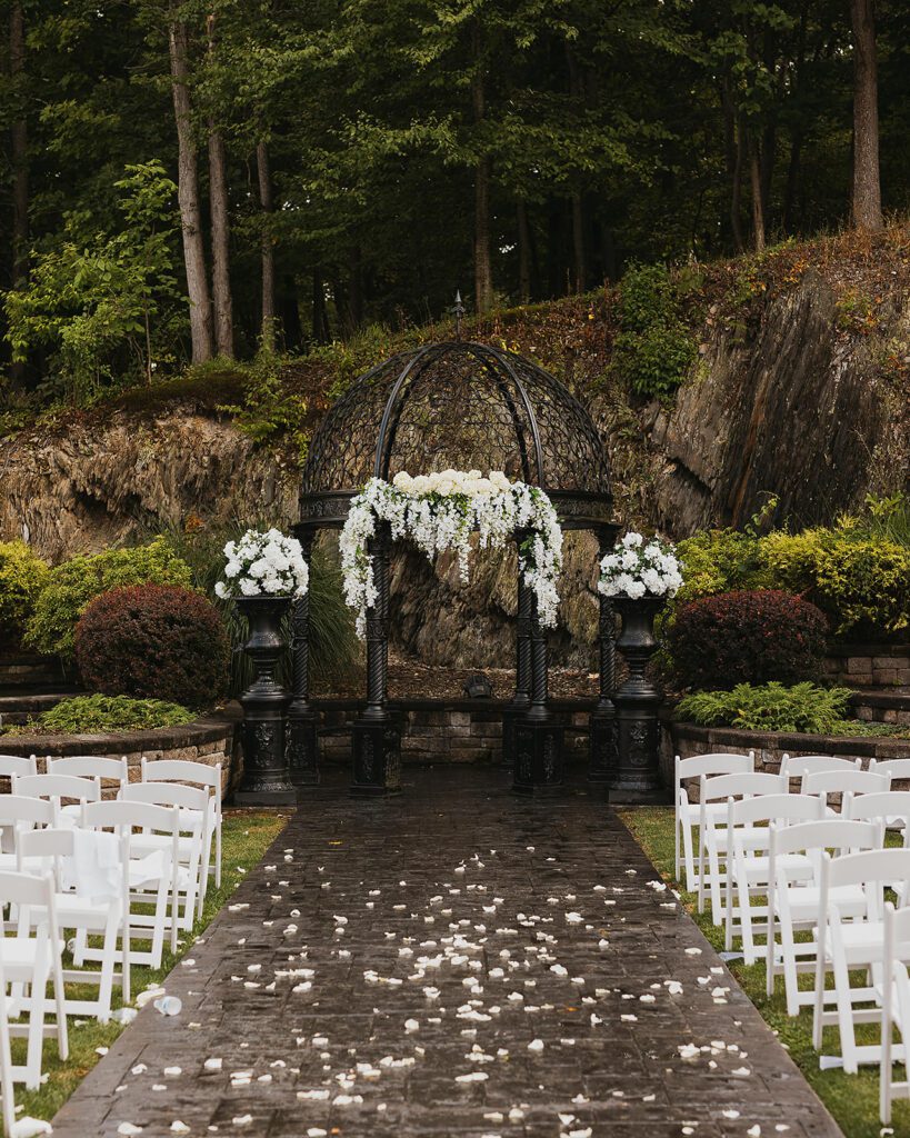 A beautifully ornate black metal gazebo is adorned with cascading white floral arrangements for a Stroudsmoor Country Inn wedding ceremony