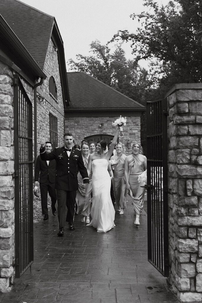 The bride and groom and their wedding party walking in front of a beautiful stone mansion - the Stroudsmoor Country Inn