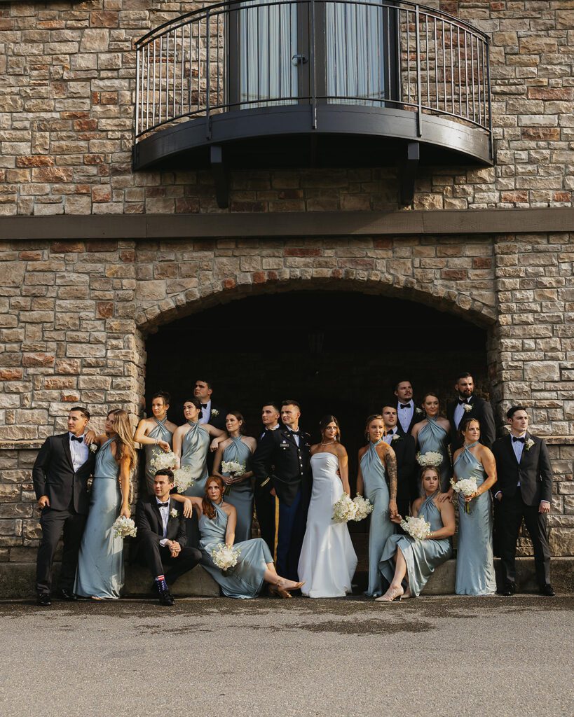 The bride and groom and their wedding party posing in front of a beautiful stone mansion - the Stroudsmoor Country Inn