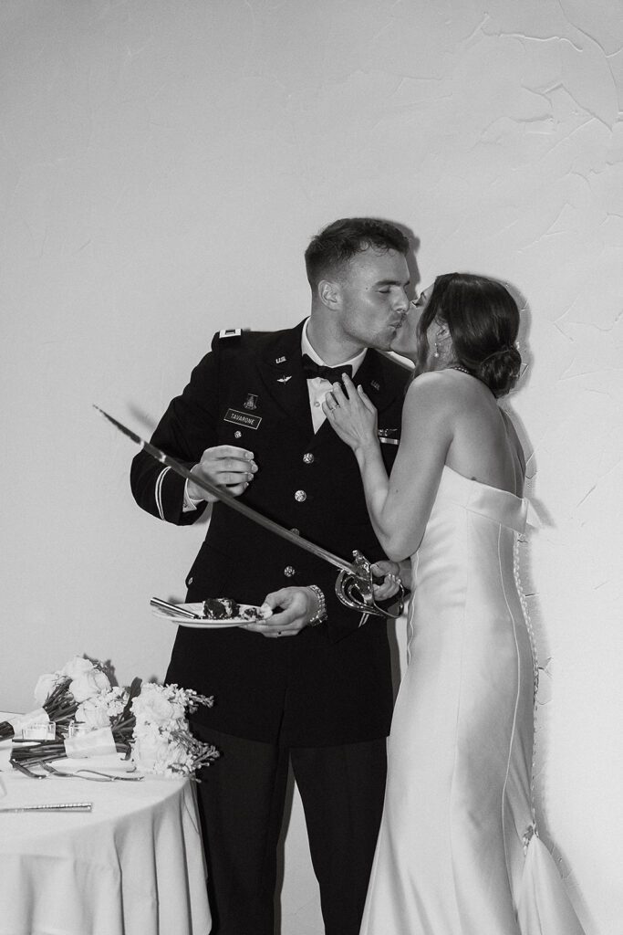 The bride and groom cut their multi-tiered wedding cake together using a ceremonial sword