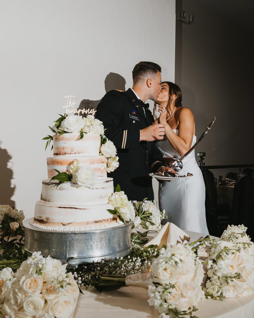 The bride and groom cut their multi-tiered wedding cake together using a ceremonial sword